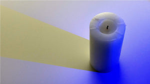 Candle with a blue light on it casting a yellow shadow 