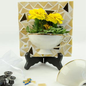 tea cup cut in half and on a mosaic background being used a flower planter
