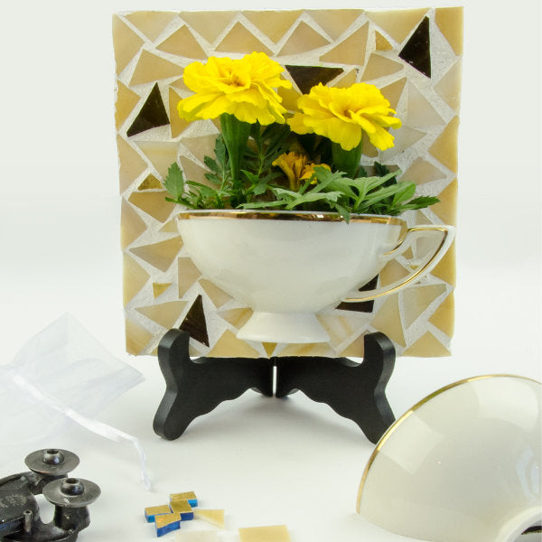 tea cup cut in half and on a mosaic background being used a flower planter